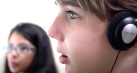 A blind boy listens to something with headphones on.