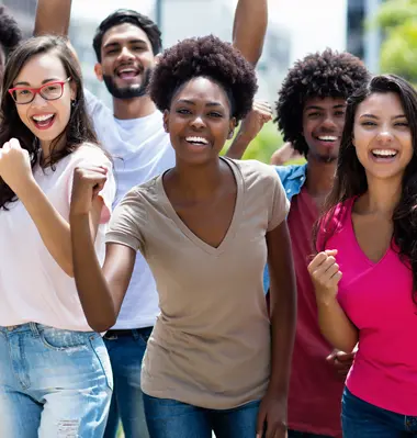 A diverse group of young people pump their fists in joy